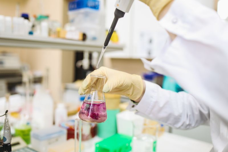 Gloved hands pipetting a sample in a forensic chemistry laboratory