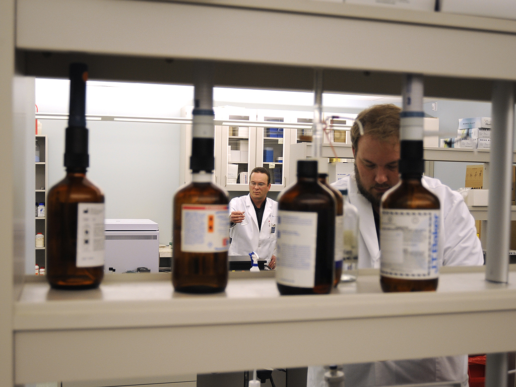 Forensic chemistry laboratory with scientists analysing samples in white lab coats