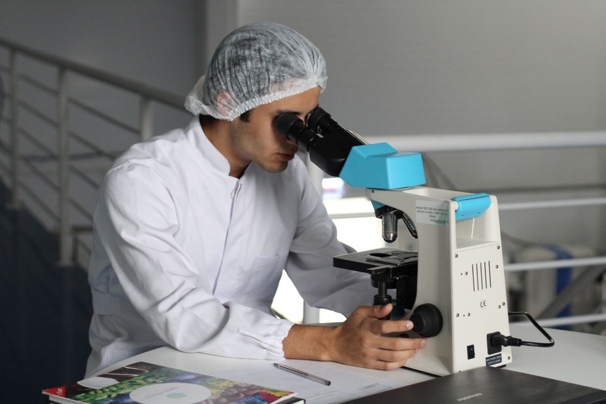 Forensic analyst examining a specimen through a laboratory microscope