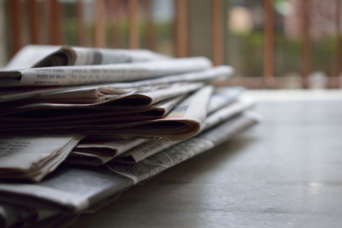 Stacked newspapers representing crime reporting and archival press coverage
